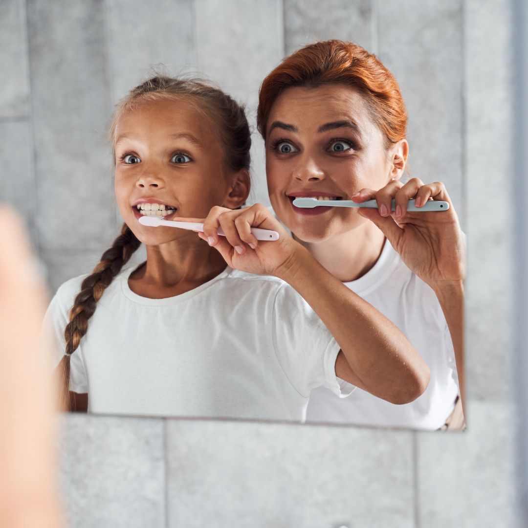 Little girl brushing teeth with her mom