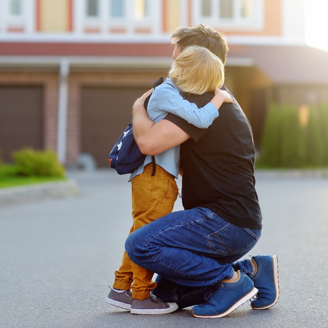 Son hugging dad in driveway