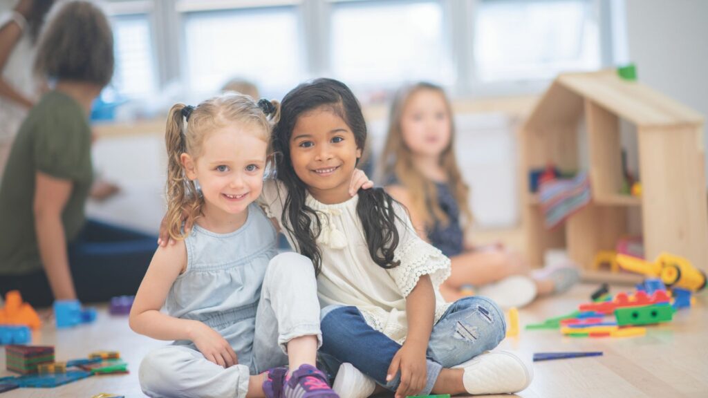 Two little girls hug and smile for the camera