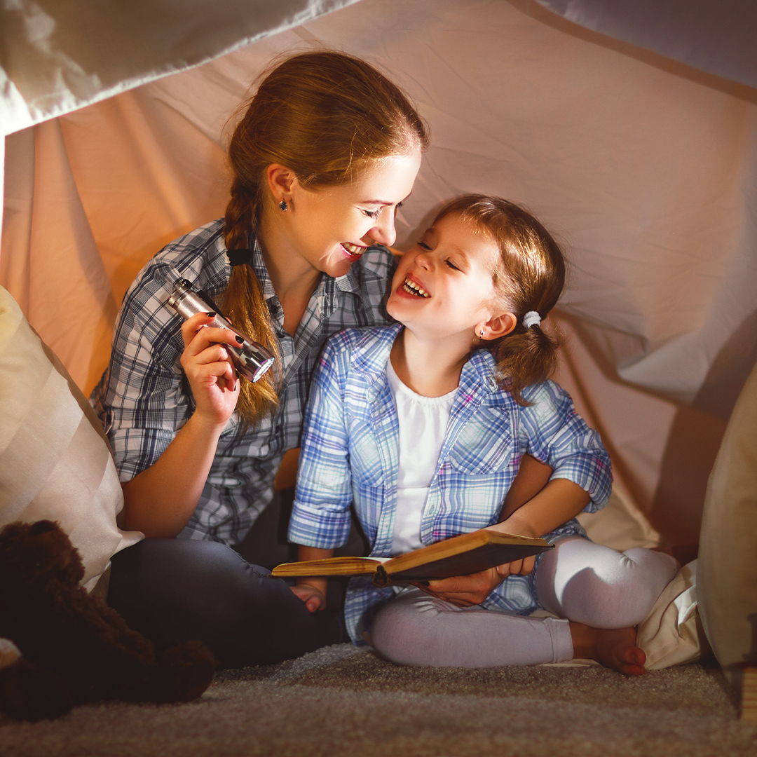 a mom and kid laughing while camping indoors