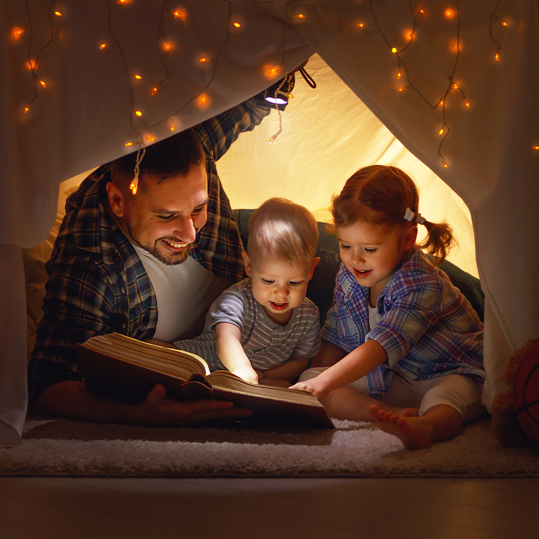 a father and his two kids indoor camping with lights
