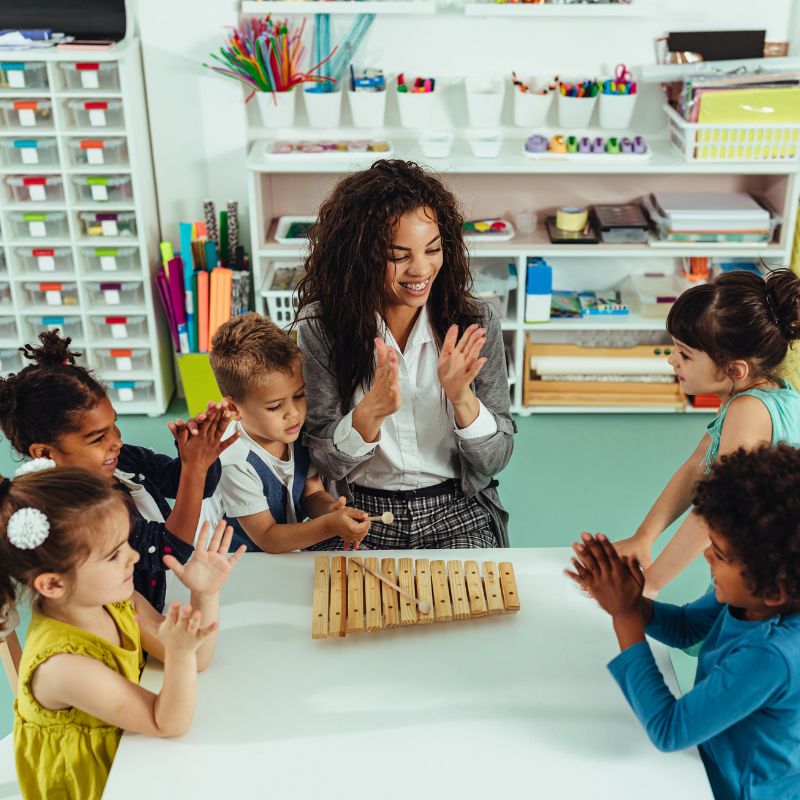 childcare teacher clapping with children