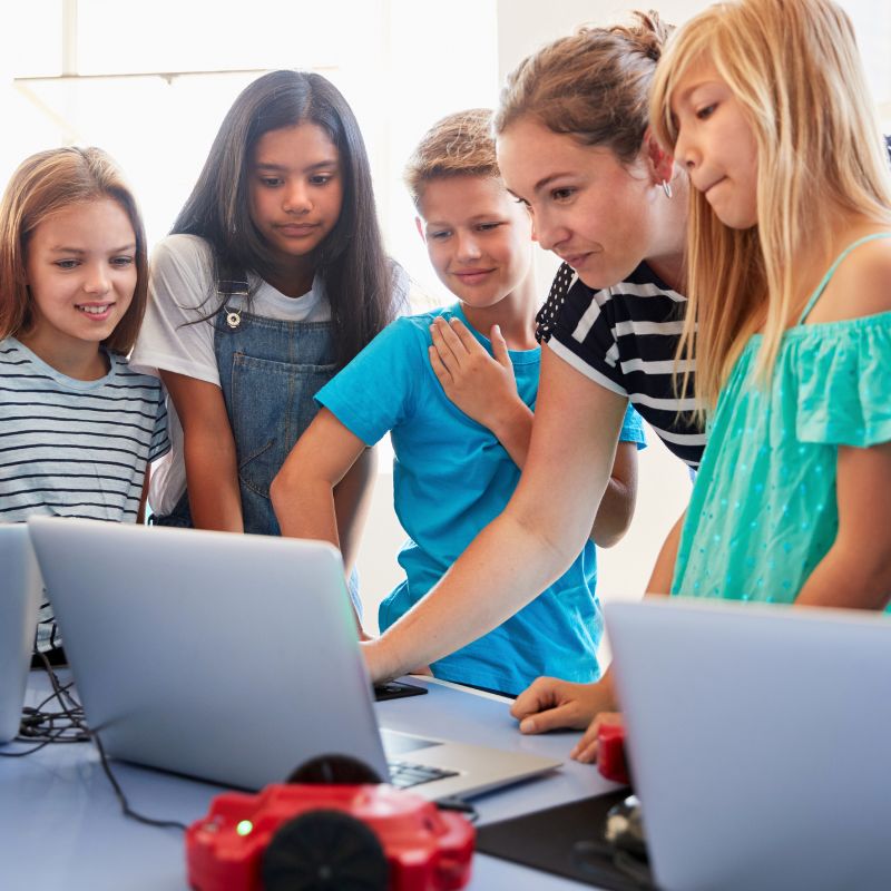 after school educator helping kids on computers
