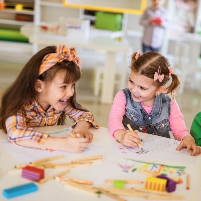 two preschool girls smiling at each other