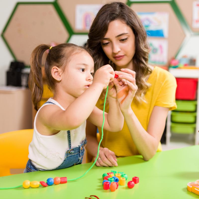 preschool teacher doing craft activity with girl